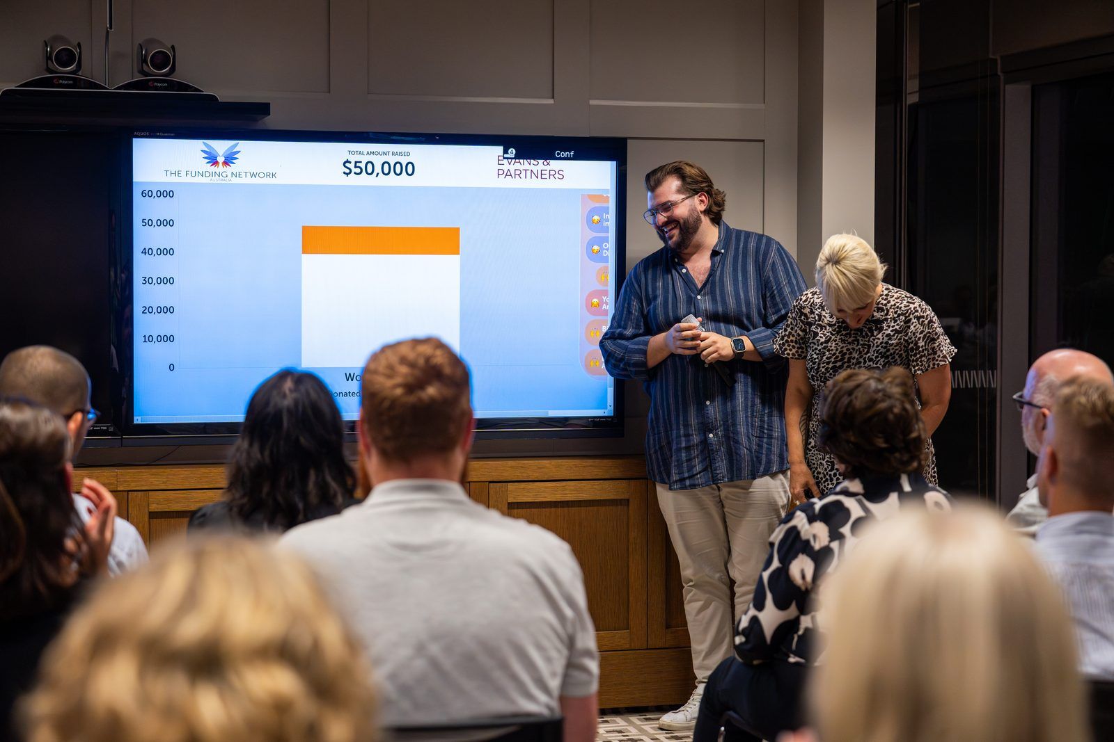 Rick Cohen gesturing with both arms mid-talk in front of an impact slide